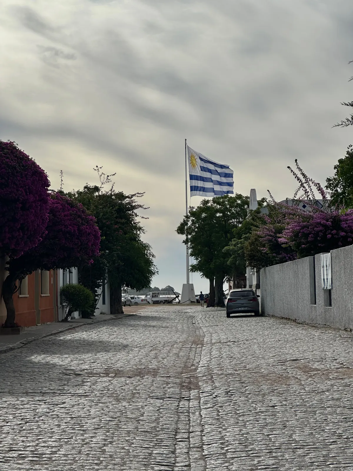 A cobblestone street in Colonia ending at the Uruguayan flag