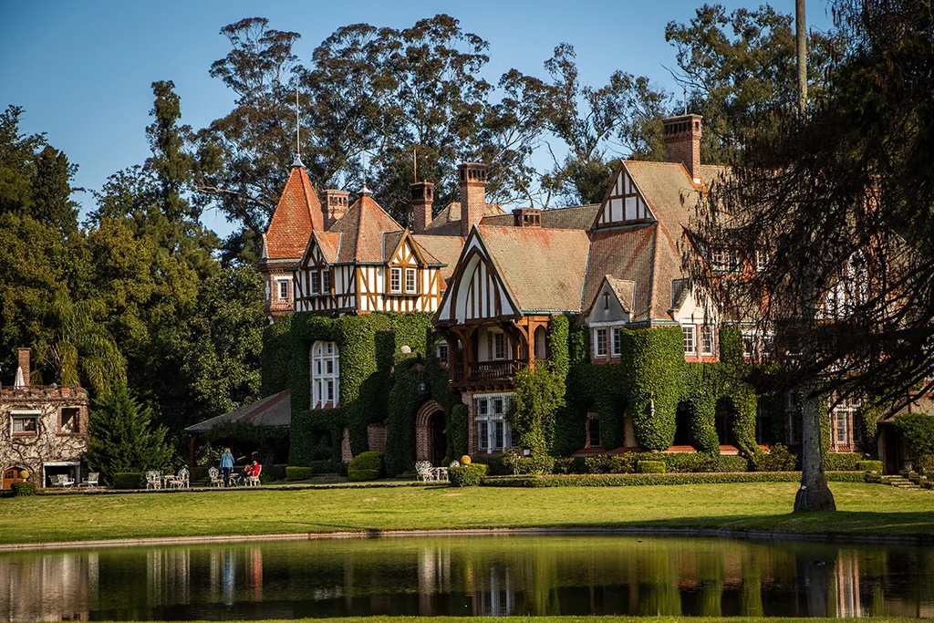 The Tudor-style main house at Estancia Villa María reflected in its lake