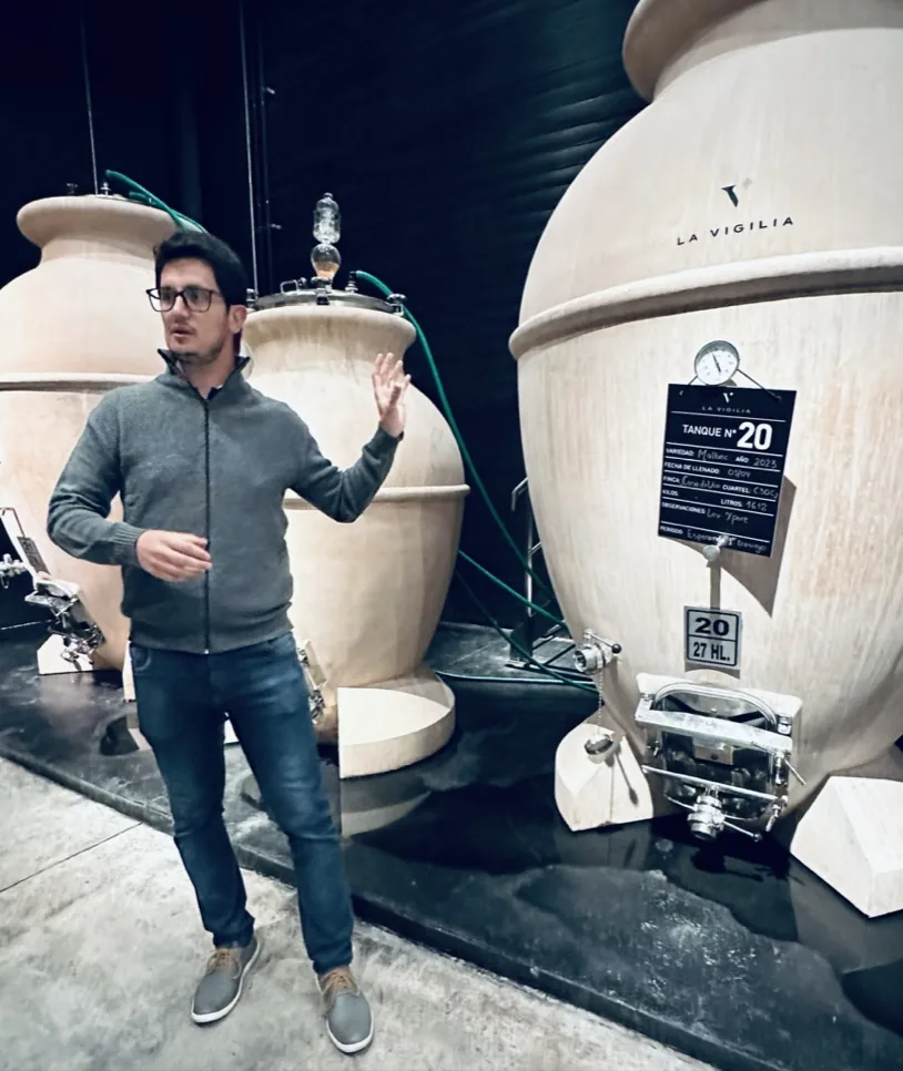 A winemaker explaining the craft beside clay wine vessels