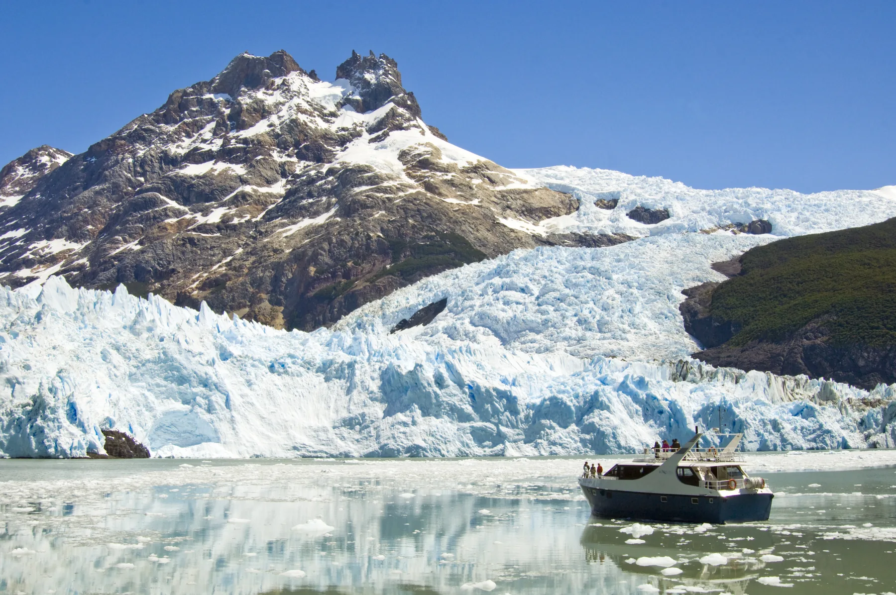 A boat sailing beside a towering glacier in Patagonia
